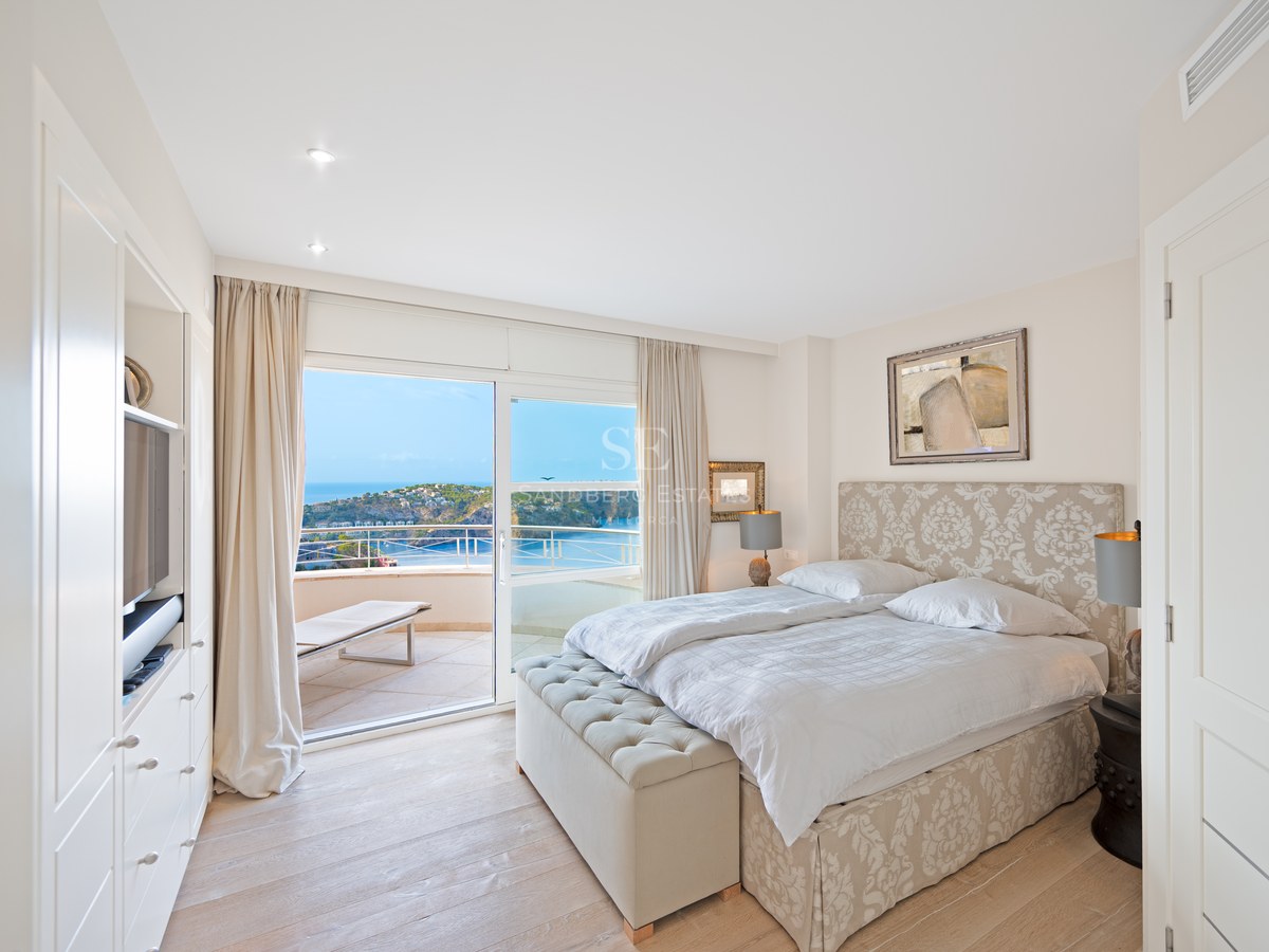 Bright master bedroom featuring a double bed with upholstered headboard and large sliding glass doors opening to a terrace.