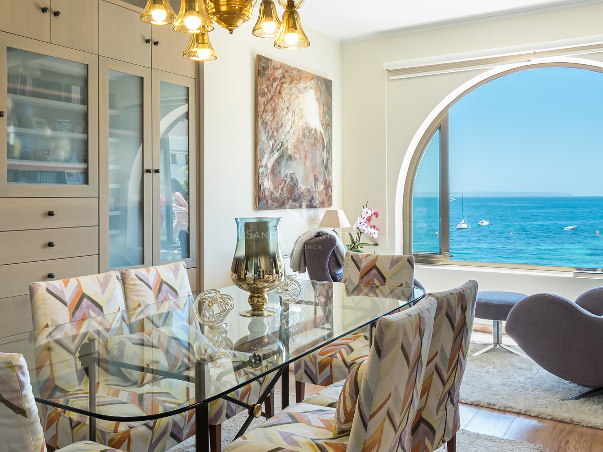 Salle à manger avec table en verre et grande fenêtre en arche offrant une vue sur la mer Méditerranée.