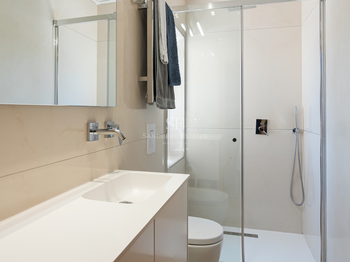 Salle de bains contemporaine avec carrelage crème, paroi de douche en verre et robinetterie chromée.