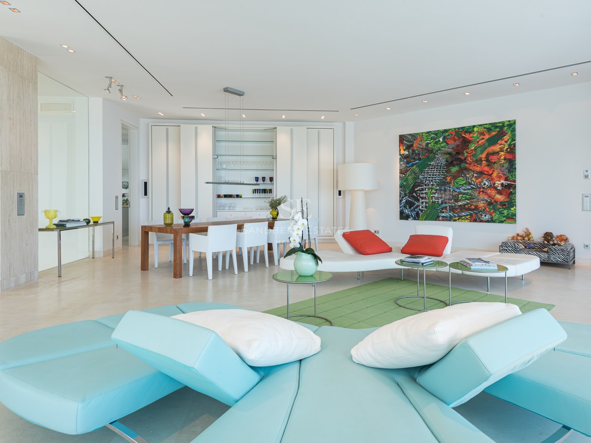 Spacious modern living room with turquoise sectional sofa, marble floors, and integrated dining area with designer furniture.