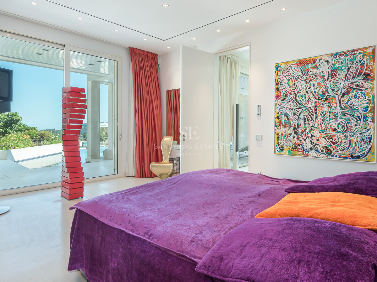 High-end master bedroom featuring purple velvet bedding, floor-to-ceiling glass doors, and contemporary art.