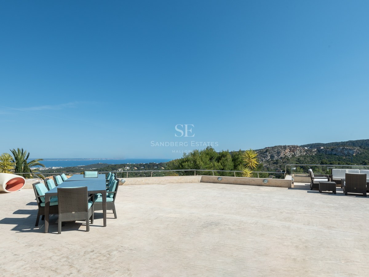 Spacious stone-paved terrace with outdoor dining and lounge areas overlooking the Mediterranean coast.