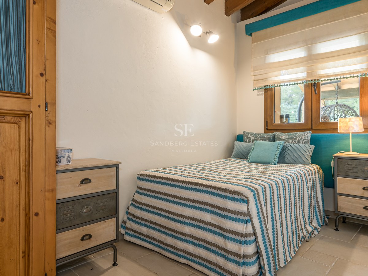 Une chambre avec un lit à rayures, une tête de lit turquoise, des meubles en bois et des tables de chevet industrielles.