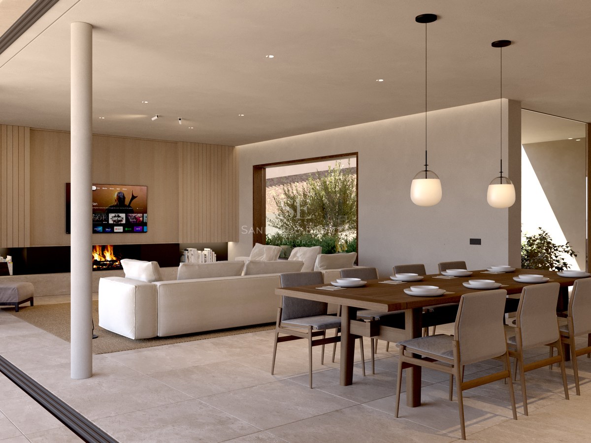 Pièce moderne à aire ouverte avec grande table à manger, canapé blanc, cheminée et baies vitrées du sol au plafond.