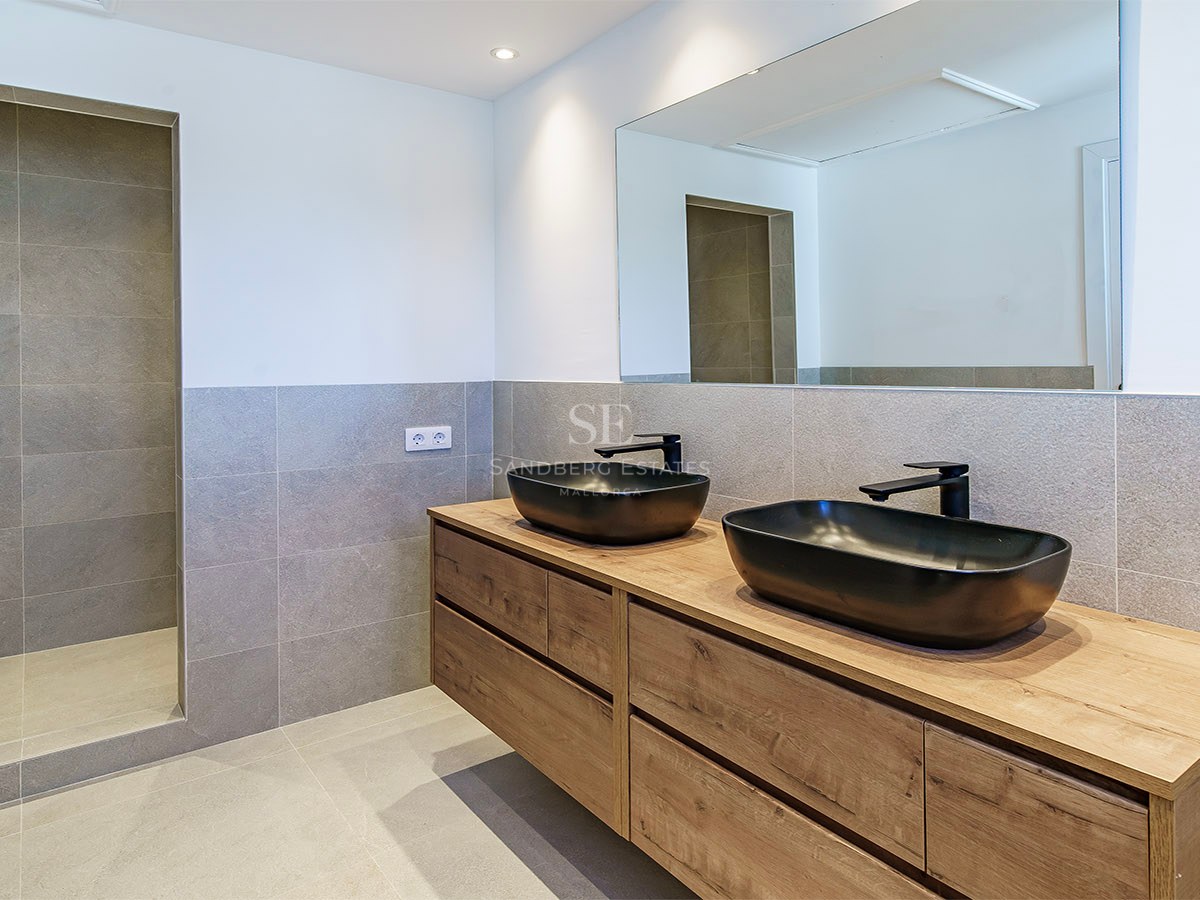 Salle de bains contemporaine avec carrelage gris, meuble en bois, vasques noires et douche à l'italienne.