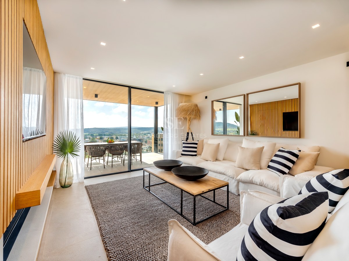Salón contemporáneo con paneles de roble, sofás blancos y grandes ventanales que dan a una terraza con vistas.