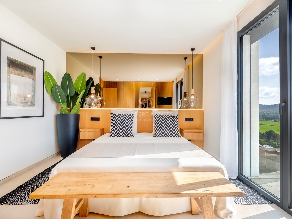 Dormitorio contemporáneo con cabecero de madera, lámparas de cristal y grandes ventanales con vistas al paisaje.