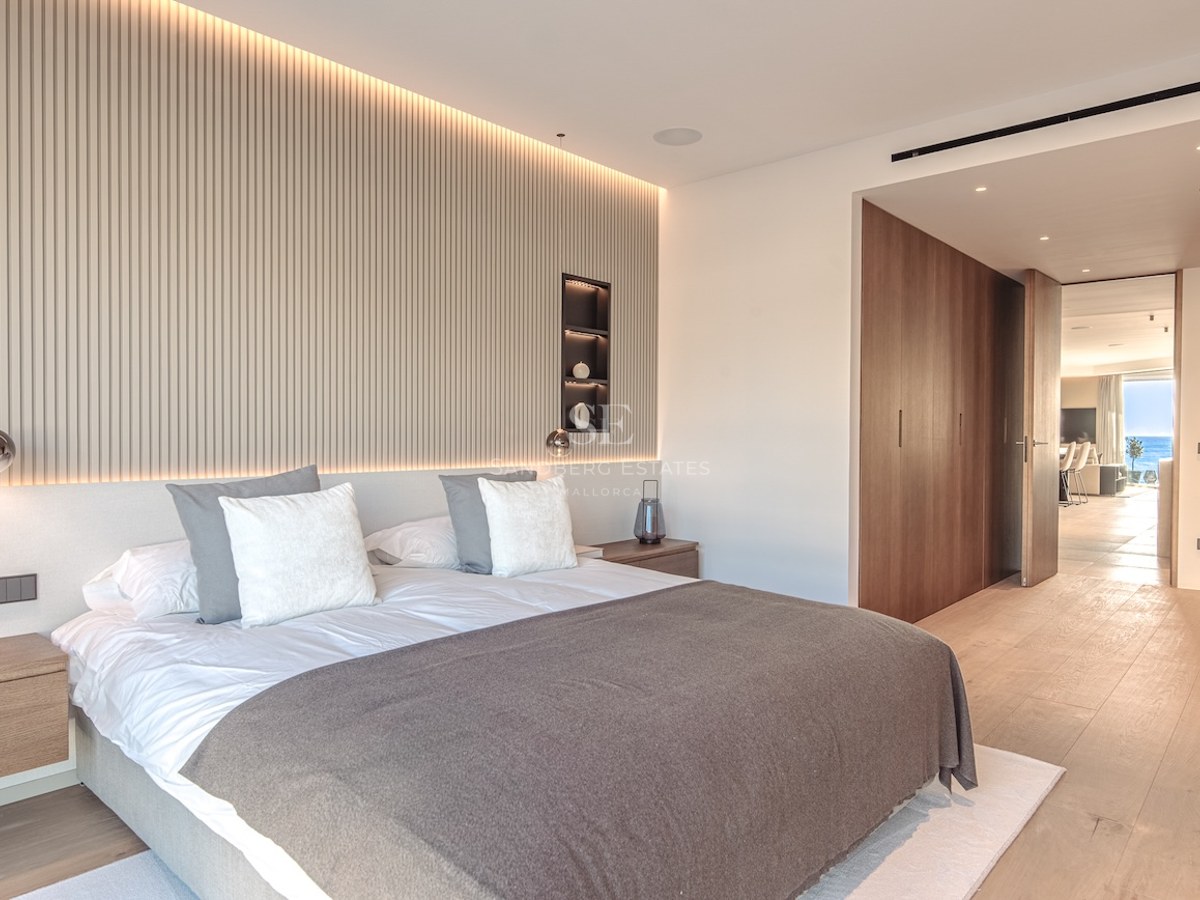 Luxury bedroom featuring a slatted wood accent wall, indirect LED lighting, oak floors, and minimalist furniture.