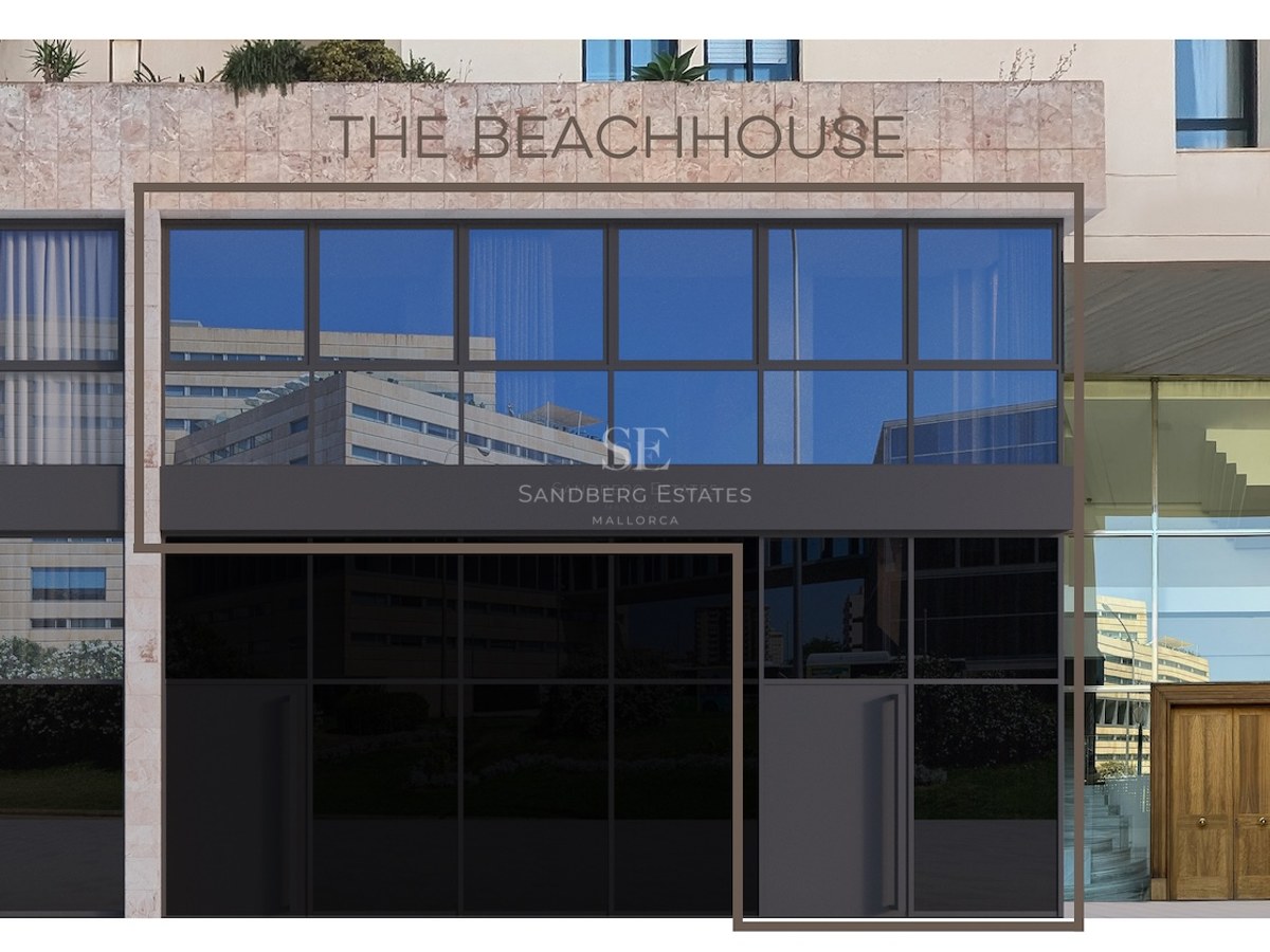 Contemporary building facade with large glass panels and natural stone cladding featuring 'THE BEACHHOUSE' signage.