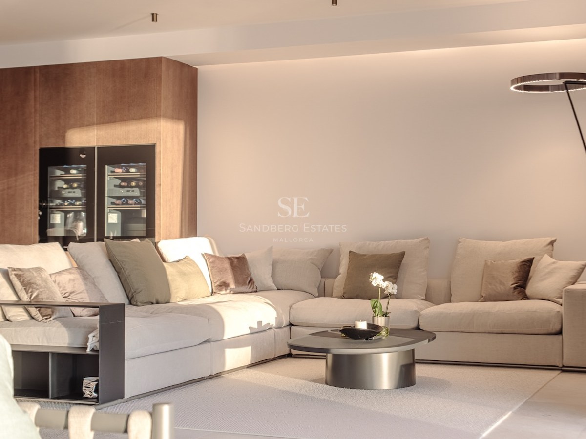 Modern living room featuring a large beige modular sofa, integrated glass wine fridge, and designer halo floor lamp.