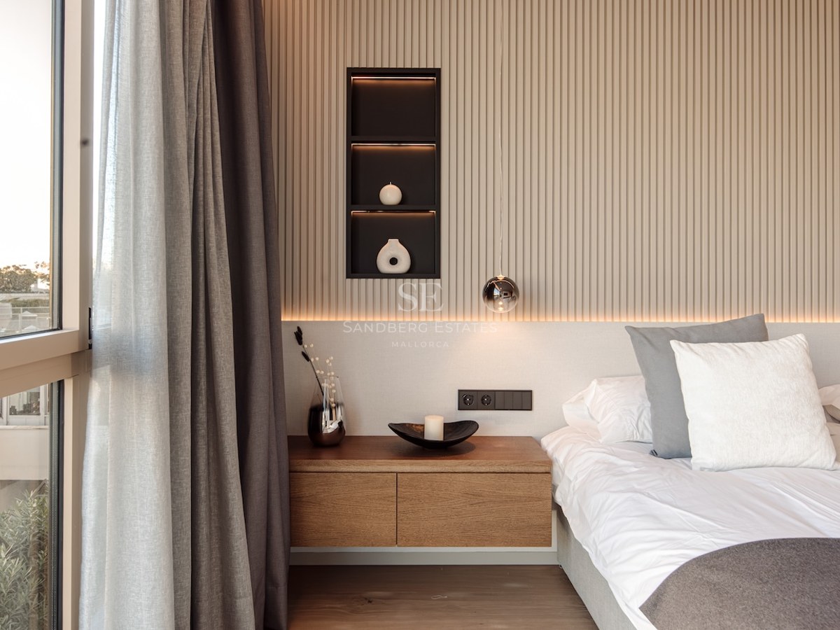 Modern bedroom featuring a slatted wood wall, floating oak nightstand, and large window with grey curtains.