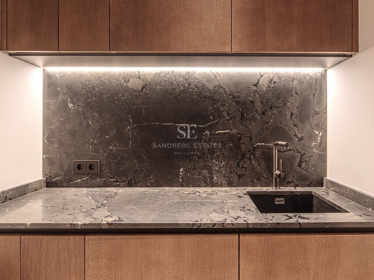 Close-up of a kitchen featuring dark marble backsplash, wooden cabinets, and integrated LED lighting.