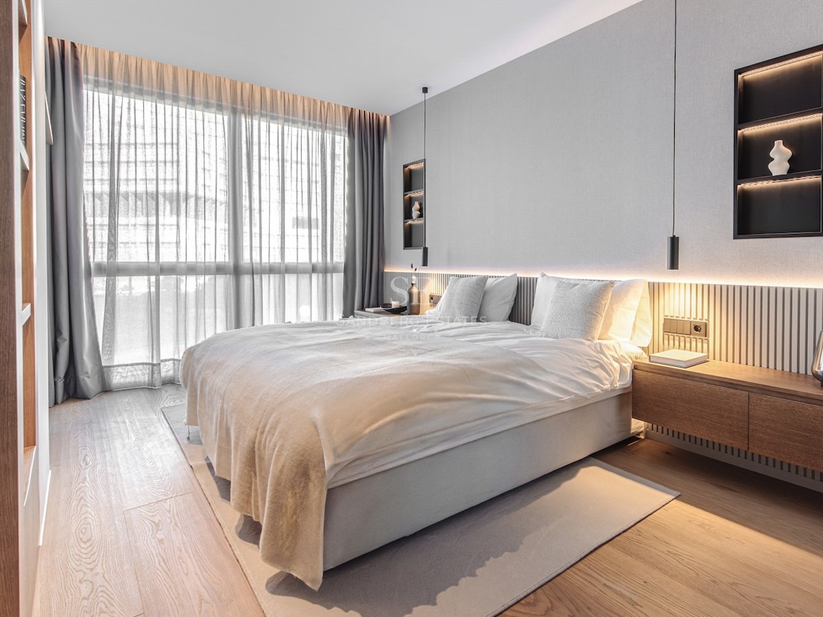 Modern bedroom featuring oak floors, floor-to-ceiling windows, and a wood-slatted headboard with integrated LED lighting.