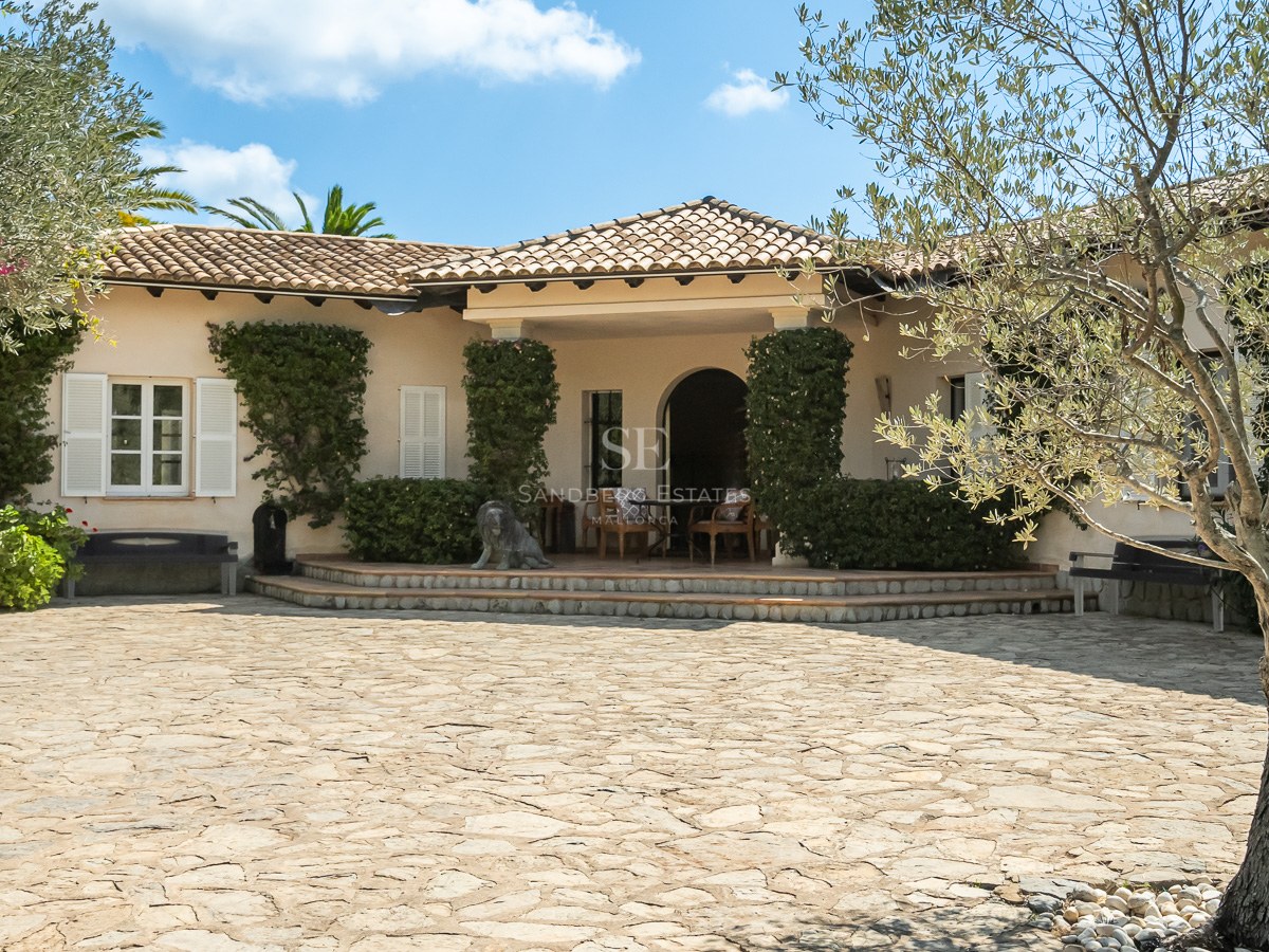 Cremefarbene mediterrane Villa mit Terrakotta-Dachziegeln, weißen Fensterläden und einem großen Naturstein-Hof.