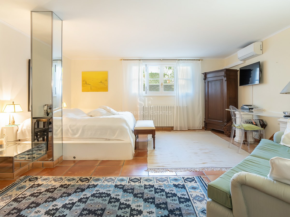 Geräumiges Schlafzimmer mit Terrakottaboden, Spiegelsäule, weißem Bettzeug, antikem Schrank und Sitzecke.