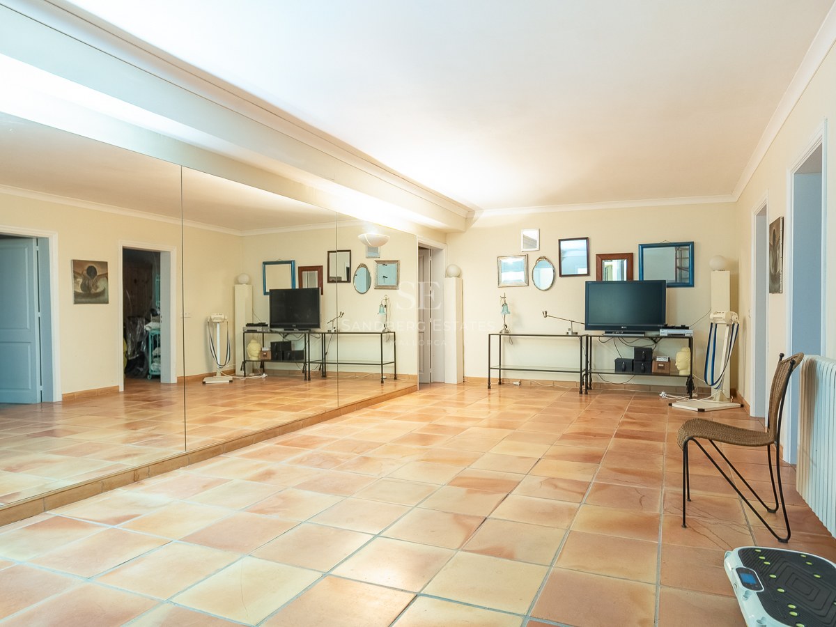 Großer Raum mit Terrakottafliesen, einer kompletten Spiegelwand und Fitnessgeräten in einer mediterranen Villa.