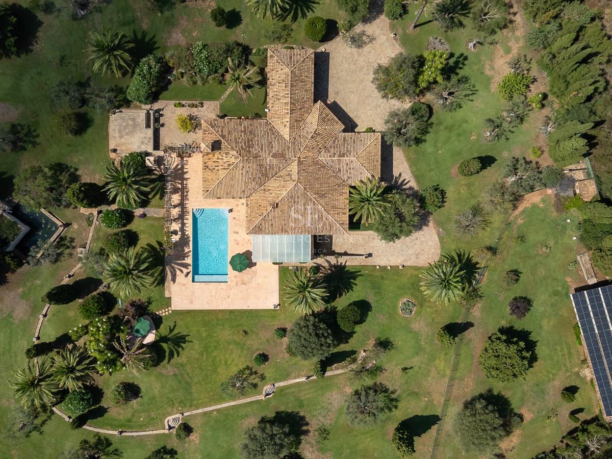 Draufsicht einer großen mediterranen Villa mit Pool, weitläufigen Gärten und Photovoltaikanlage.