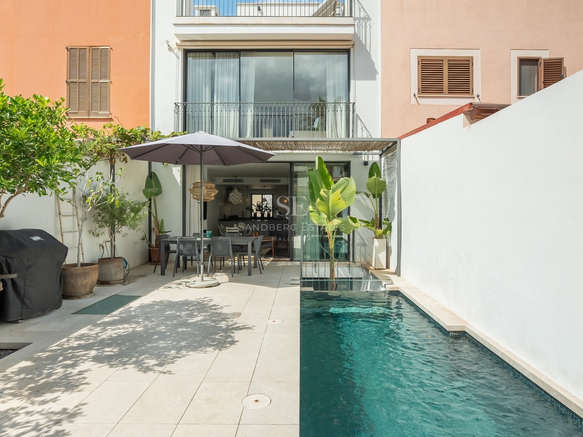 Cour extérieure moderne avec piscine, coin repas sous un parasol et murs blancs.