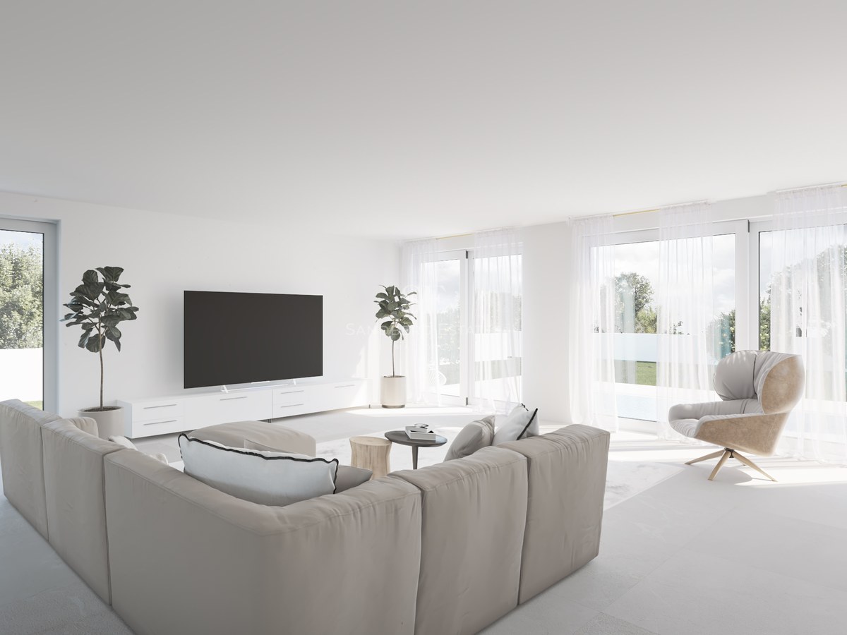 Helles Wohnzimmer mit beigem Sofa, großen Fenstern und Blick auf den Garten mit Pool.