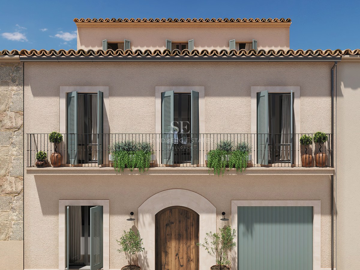 Façade à trois niveaux avec murs en stuc beige, volets vert sauge, balcon en fer forgé et porte en bois massif.