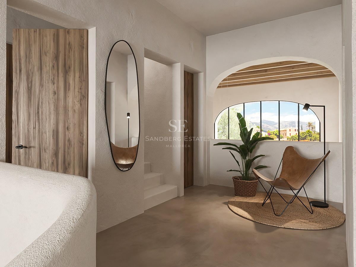 Couloir moderne avec murs texturés, chaise en cuir, miroir ovale et fenêtre voûtée avec vue sur la montagne.