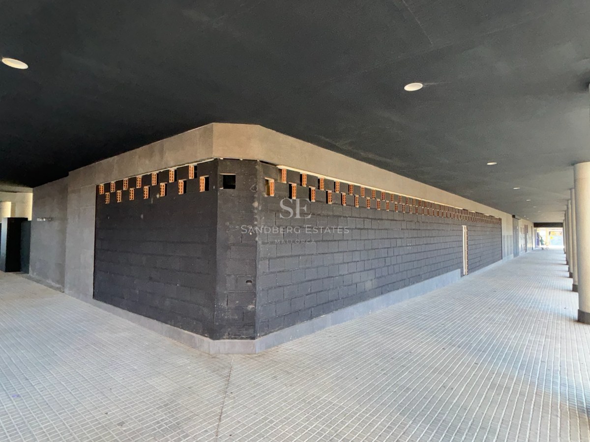 Covered walkway featuring dark block walls, concrete pillars, and recessed ceiling lighting.
