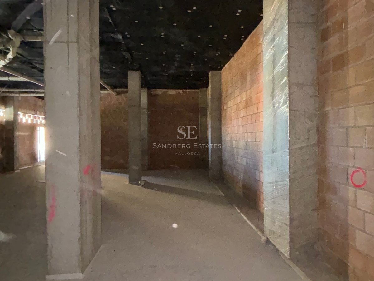 Interior view of a spacious underground parking area in its early construction phase with concrete pillars and brick walls.