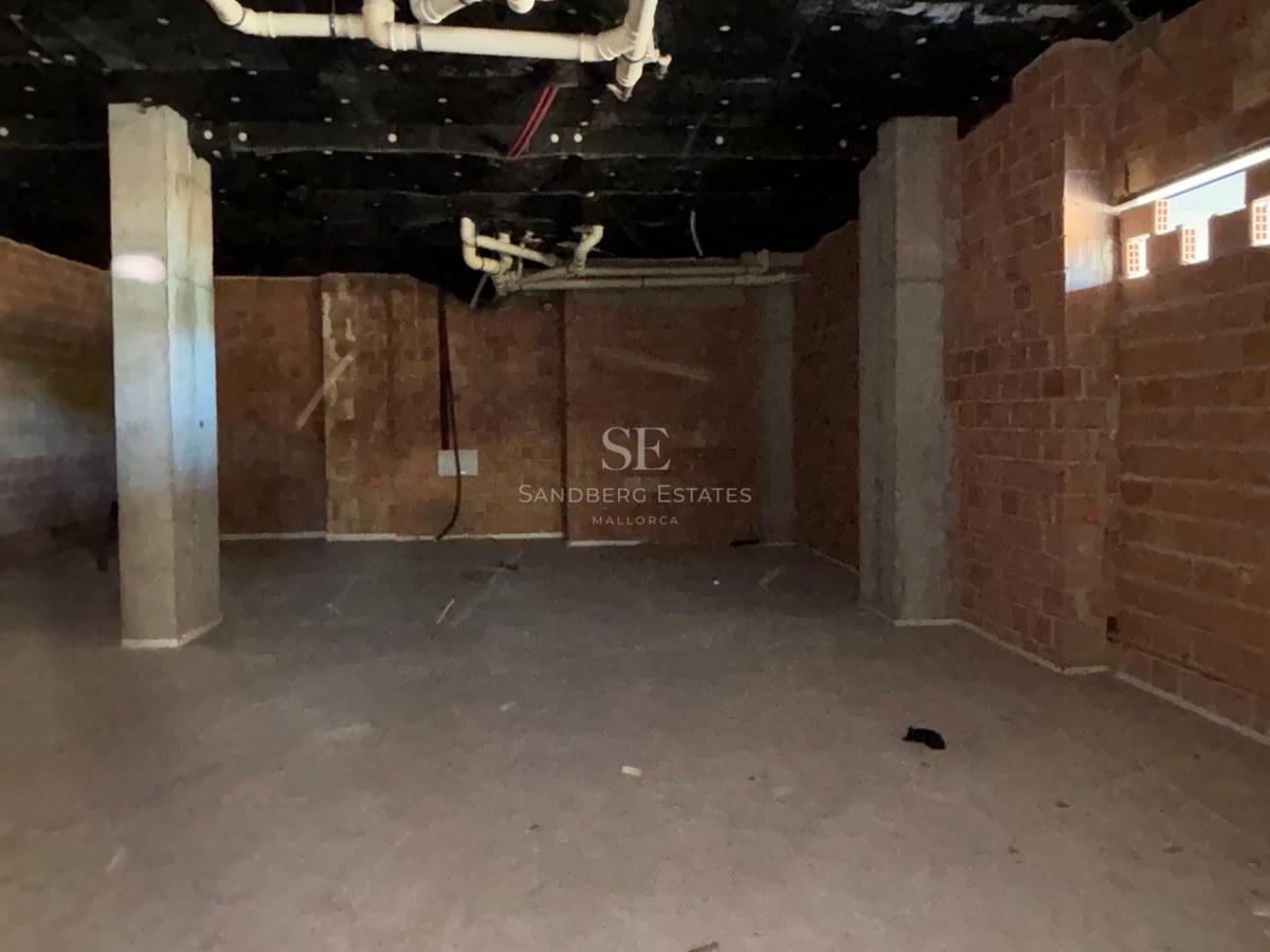 Interior room under construction with red brick walls, concrete pillars, and exposed ceiling pipes and insulation.