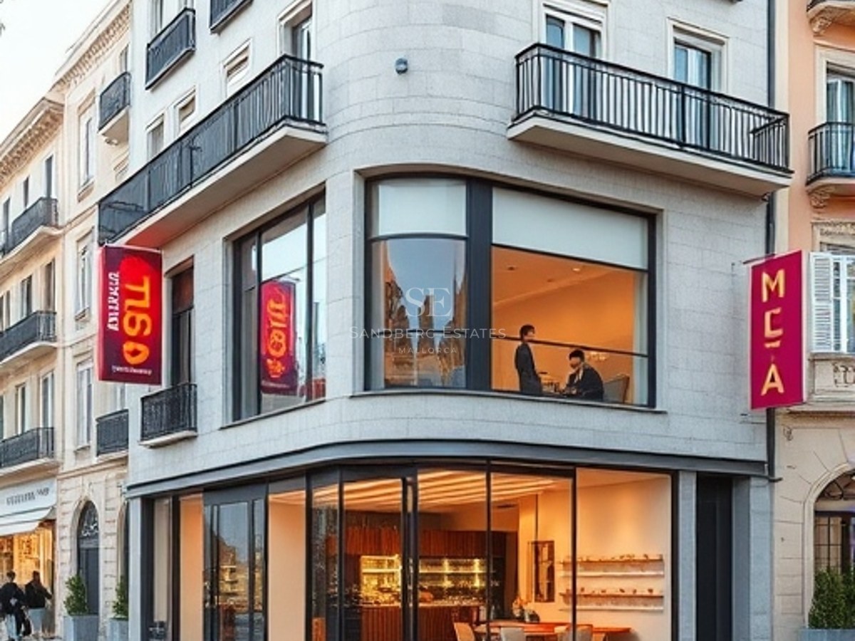 Corner view of a classic stone building with modern expansive glass storefronts and wrought iron balconies.