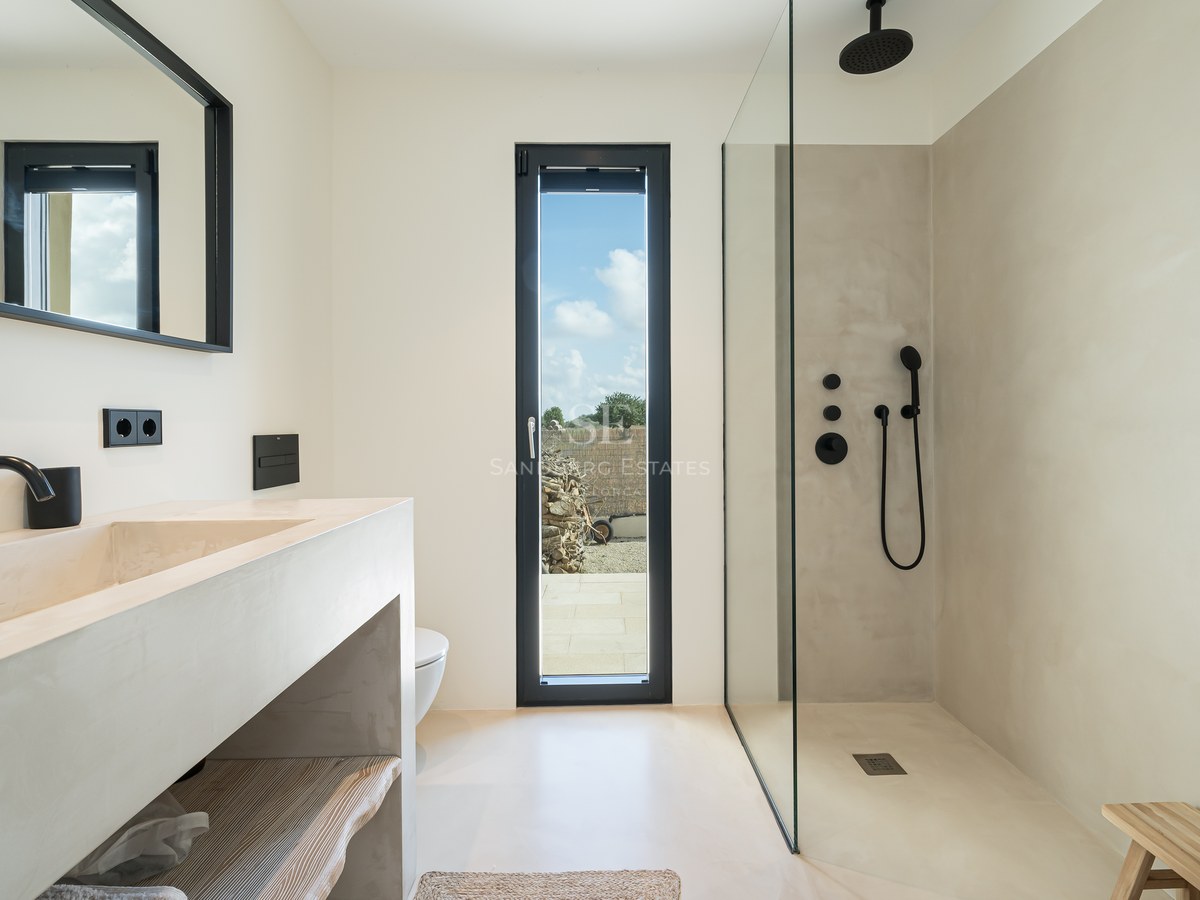 Salle de bain moderne avec plan vasque en microciment, douche à l'italienne et robinetterie noir mat.