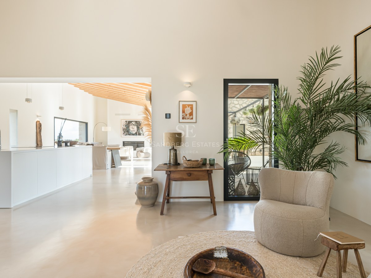 Intérieur lumineux avec sols en béton ciré, hauts plafonds, mobilier contemporain et cuisine blanche ouverte.