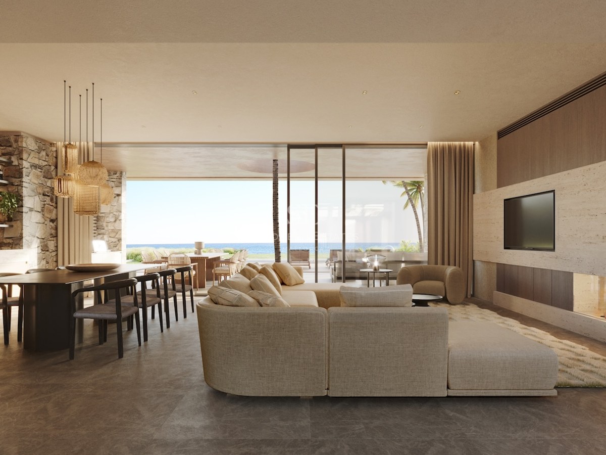 Grand salon contemporain avec canapé neutre, cheminée intégrée et baies vitrées donnant sur la mer.