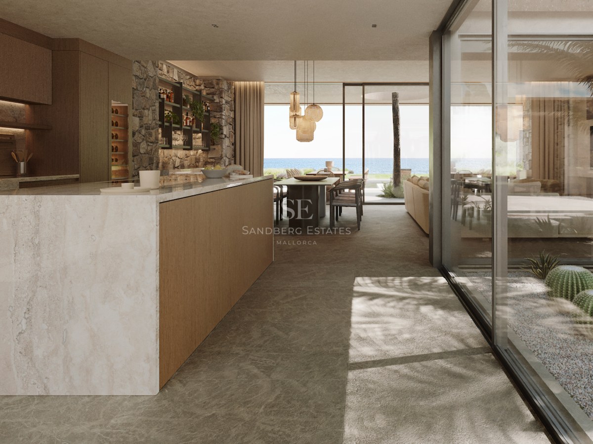 Cuisine moderne avec îlot en marbre, murs en pierre et baies vitrées donnant sur la mer Méditerranée.