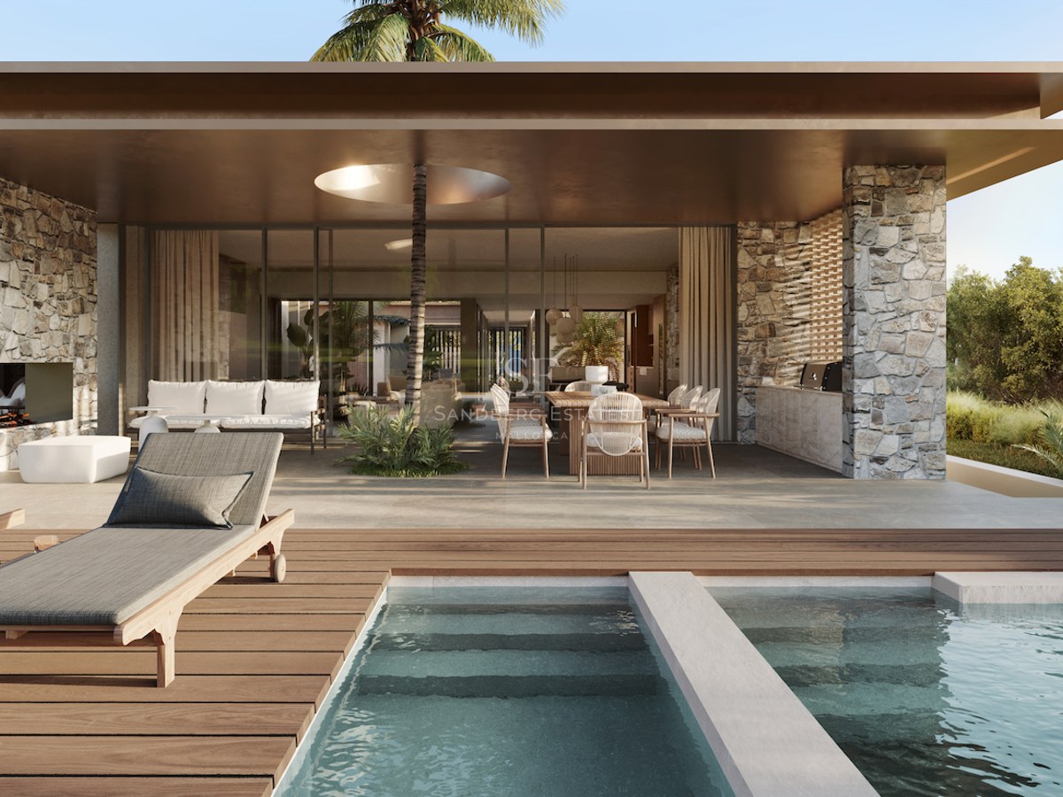 Piscine avec terrasse en bois, transats et espace couvert comprenant un coin repas et des murs en pierre naturelle.
