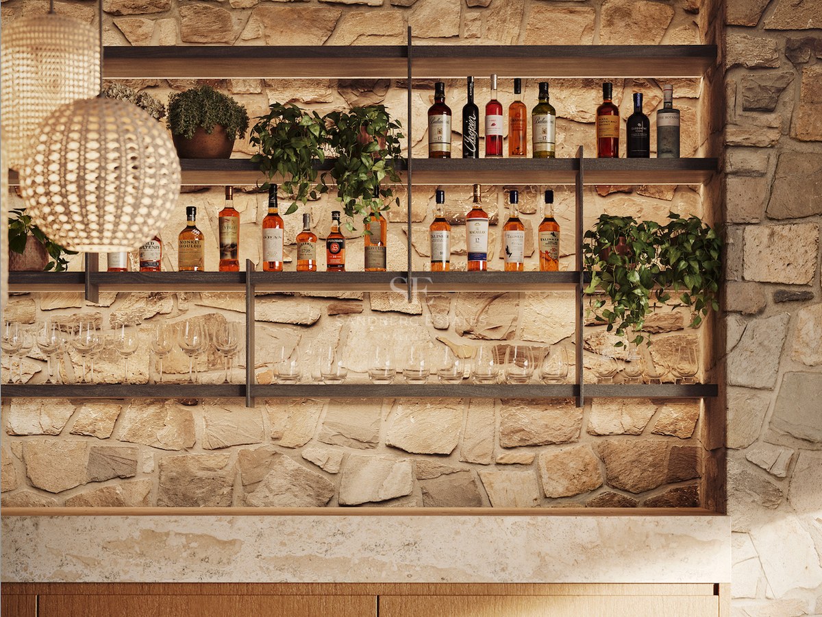 Espace bar avec mur en pierre, étagères en bois avec bouteilles d'alcool, verres et suspensions en fibres naturelles.