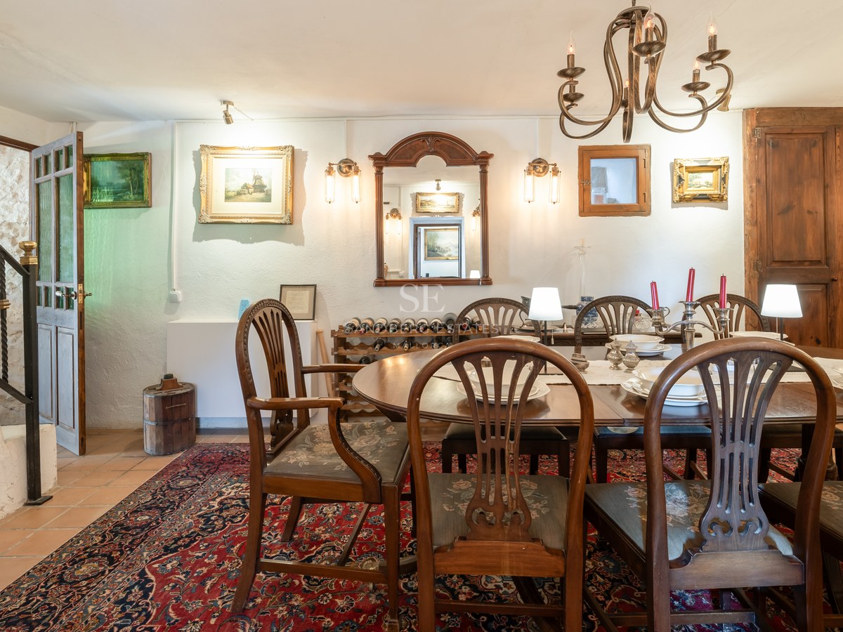 Espace dînatoire formel avec table ovale en bois, chaises de style et tapis oriental rouge.