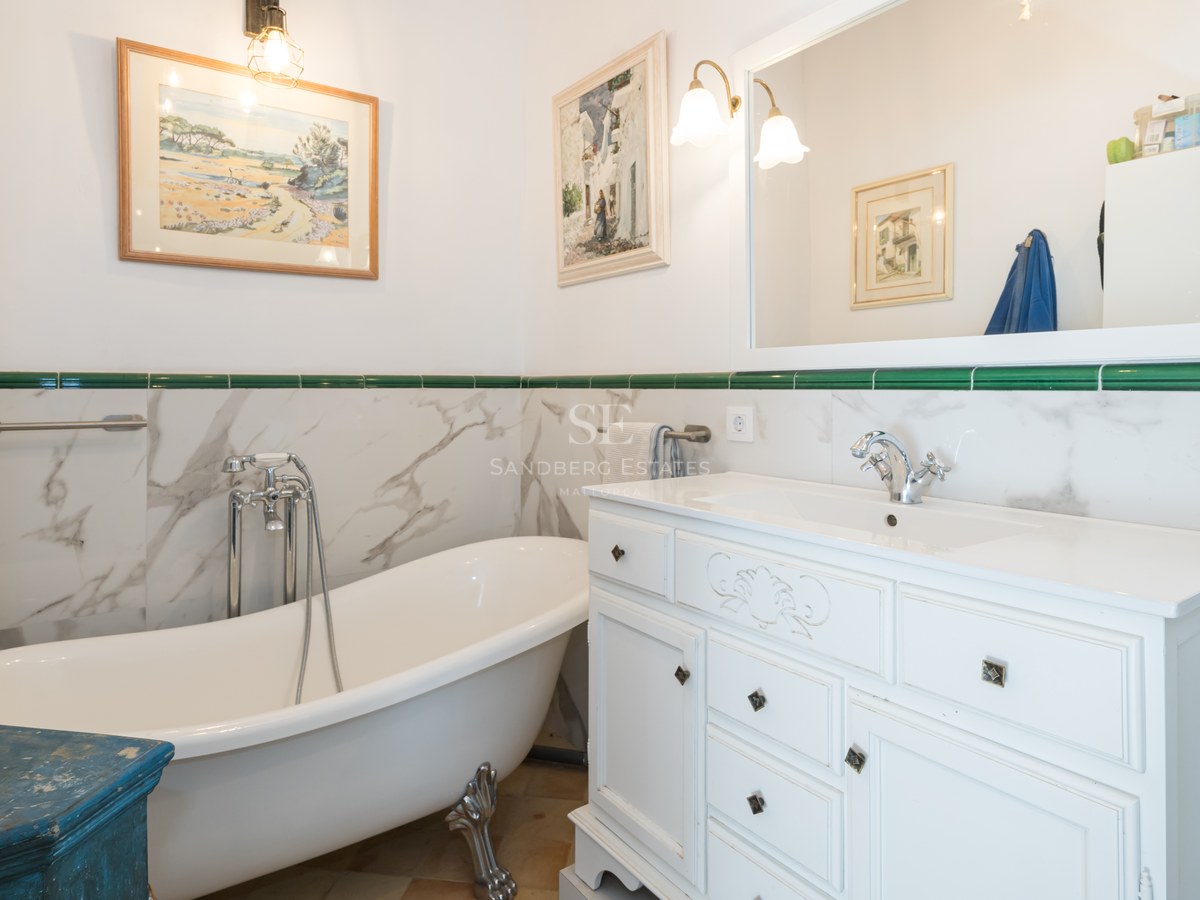 Salle de bain traditionnelle avec baignoire sur pieds, meuble vasque blanc et accents de carrelage vert.