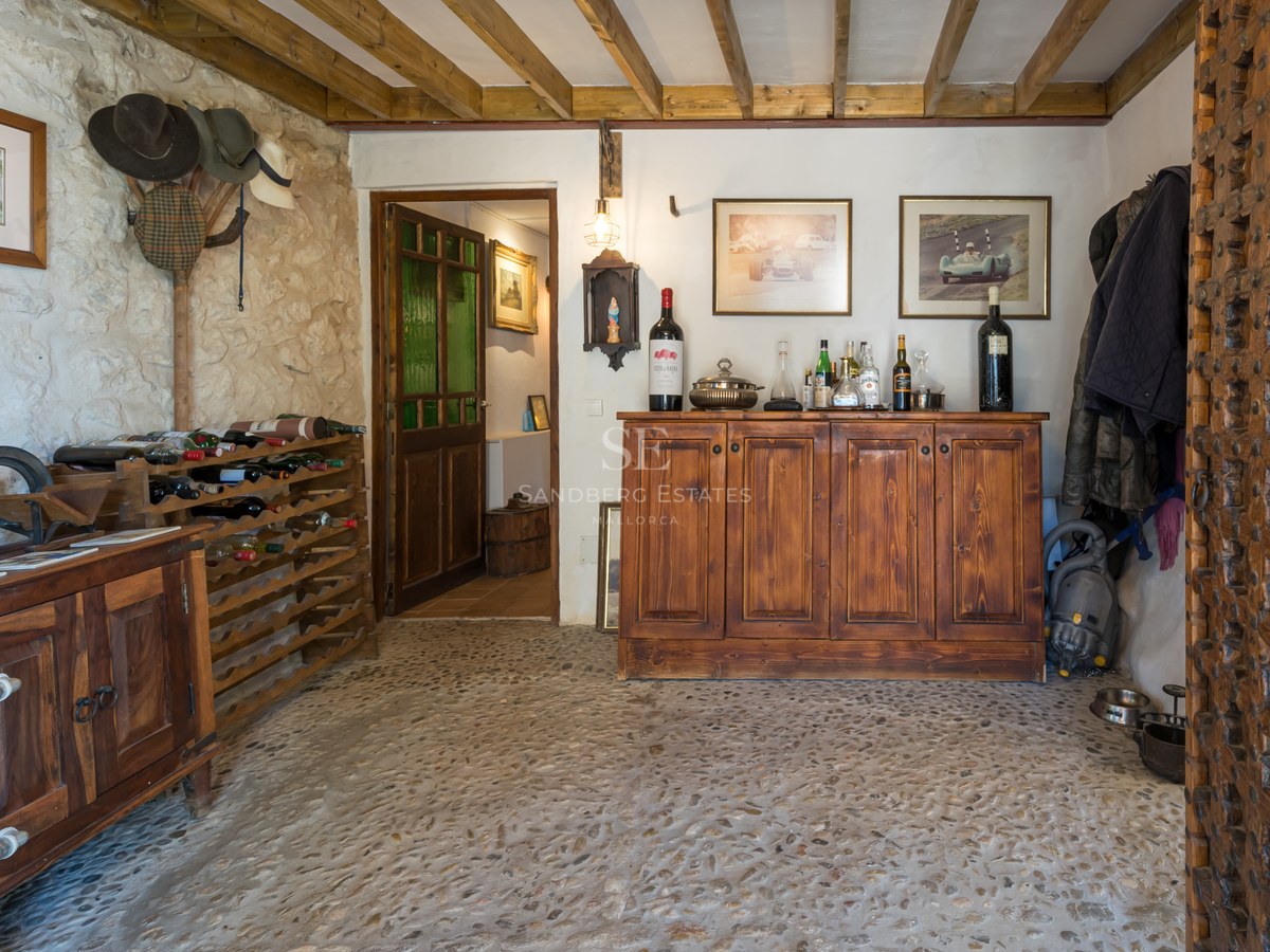Intérieur d'une cave à vin rustique avec poutres apparentes, murs en pierre et buffet en bois massif.
