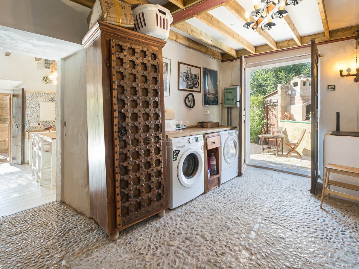 Espace buanderie avec sol en galets, armoire en bois sculpté et accès direct vers l'extérieur.