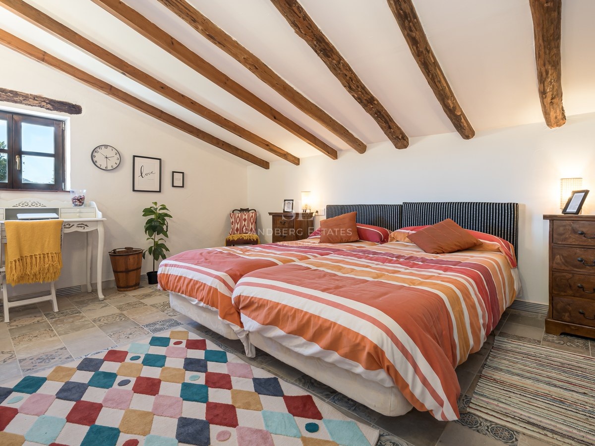 Chambre sous les combles avec poutres en bois, lits jumeaux et revêtement de sol en pierre naturelle.