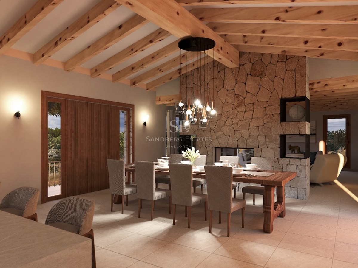 Interior view of a luxury dining room with high wooden beam ceilings, a natural stone feature wall, and a large dining table.