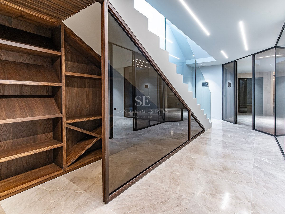 Modern interior with dark wood wine racks, polished marble floors, glass partitions, and a white LED-lit staircase.