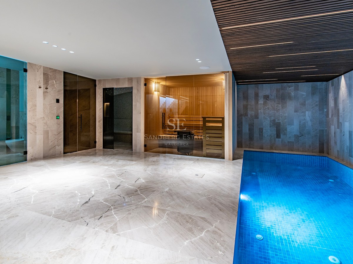 Indoor spa with a small blue pool, glass-walled sauna, and marble floors under a slatted ceiling.
