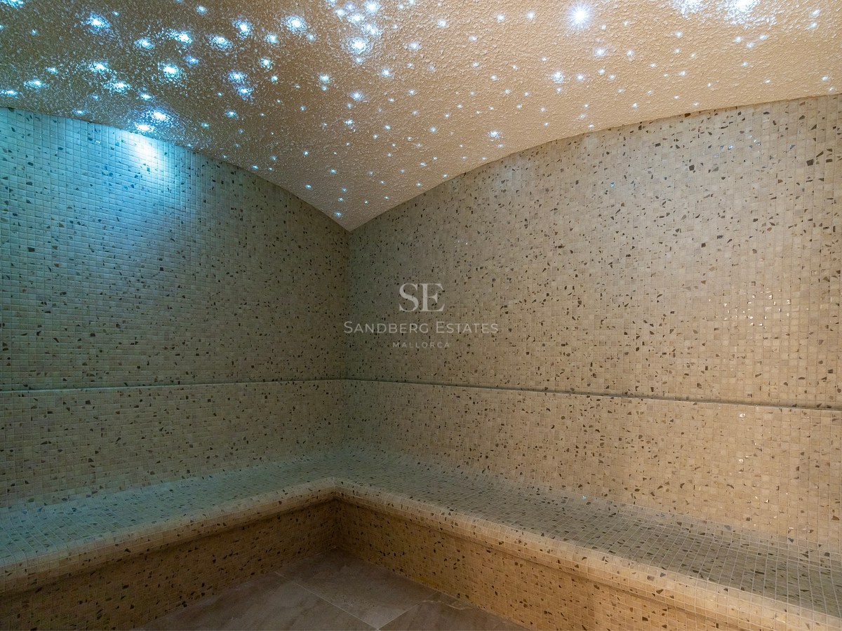 Luxury steam room featuring beige mosaic tiles and a fiber-optic starry sky ceiling lighting effect.
