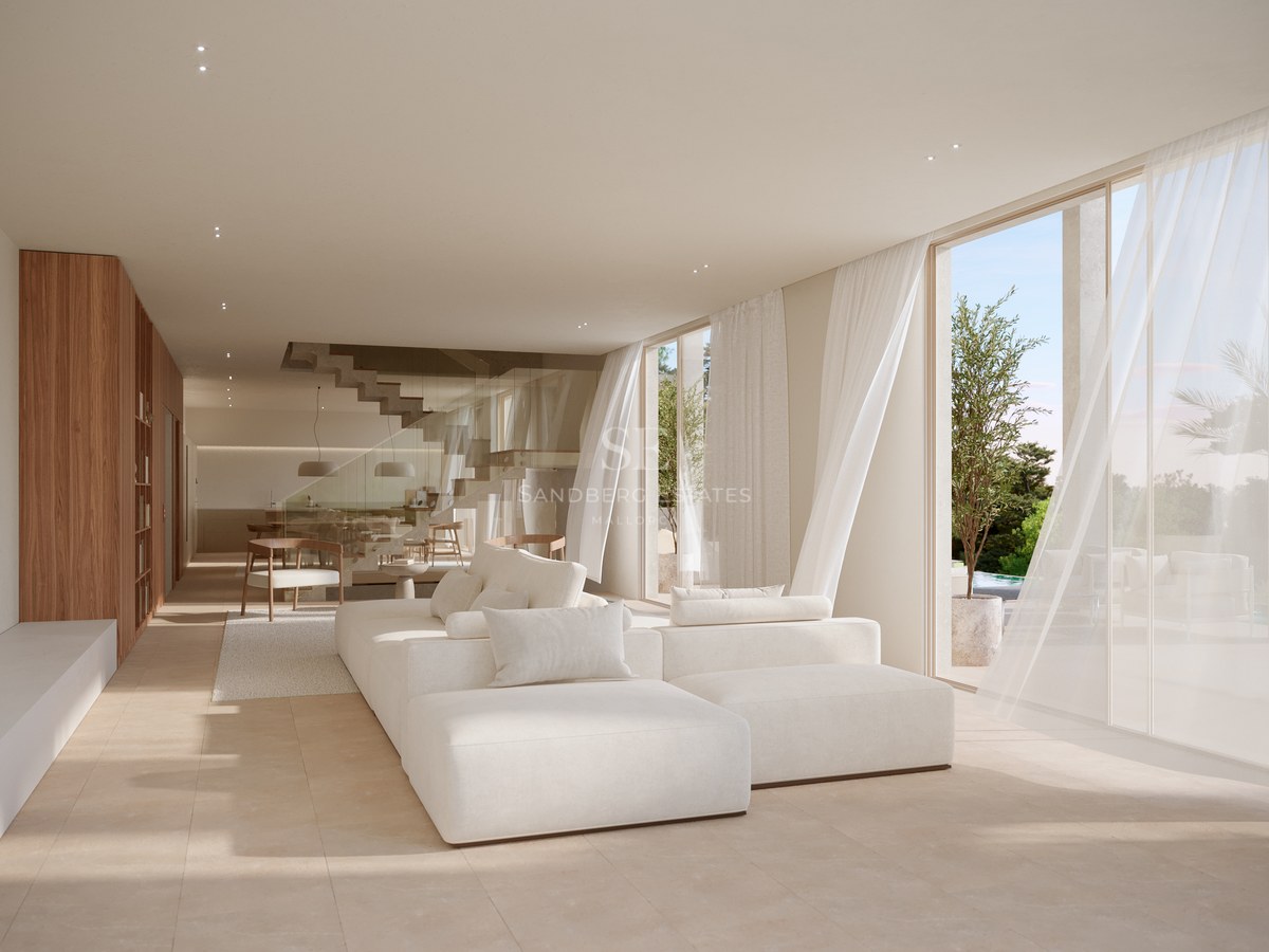 Bright living room with a large white modular sofa, floor-to-ceiling windows, and natural stone flooring.