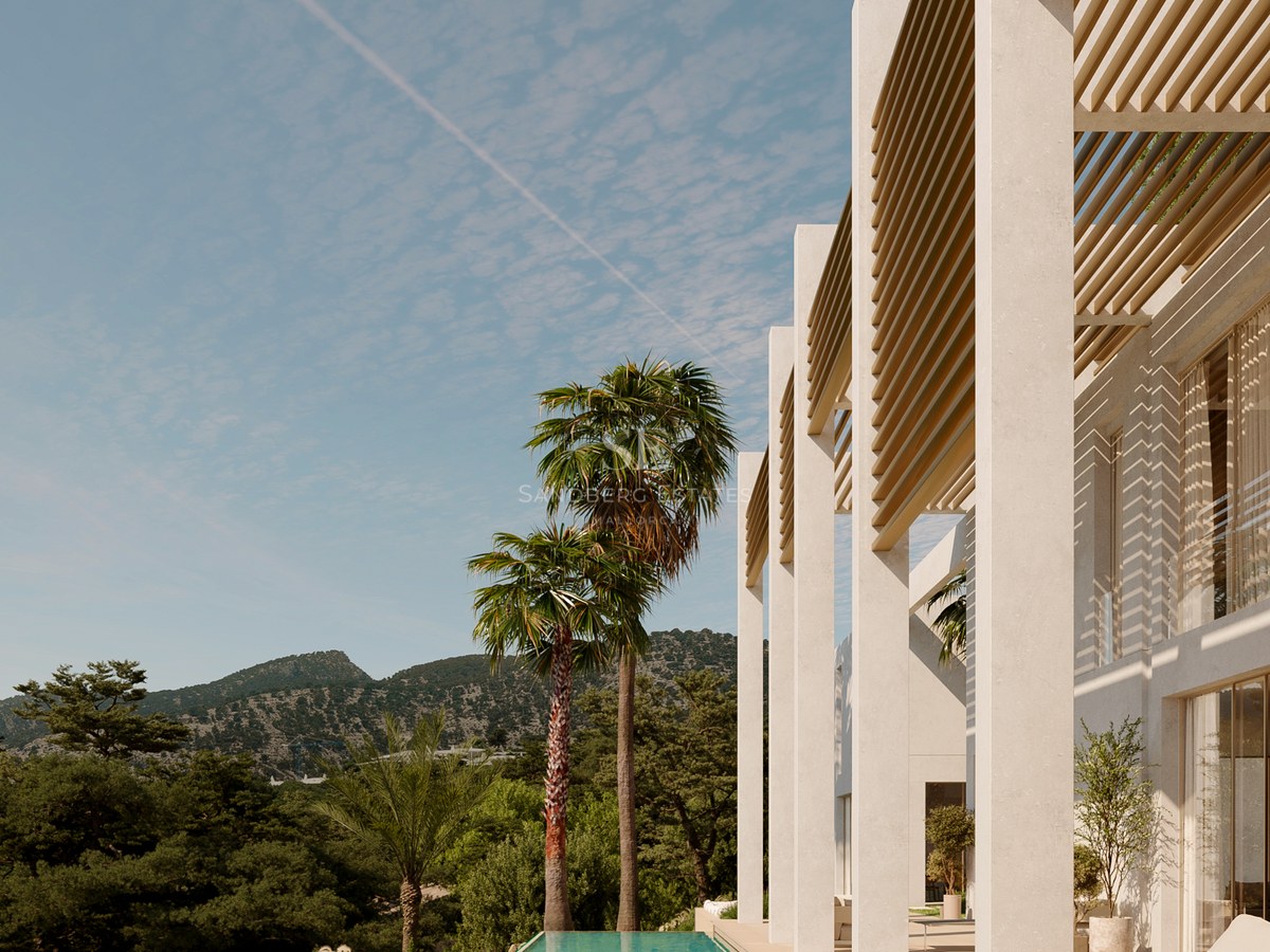 Modern white villa featuring a long infinity pool, wooden pergolas, and palm trees against a mountain backdrop.