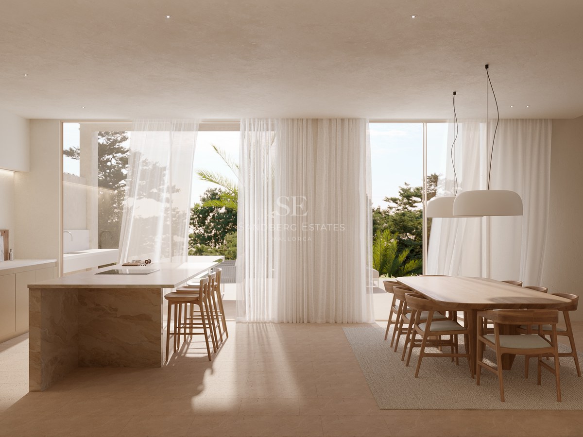 Bright kitchen with stone island, wooden dining set, and sheer curtains opening to a lush garden.