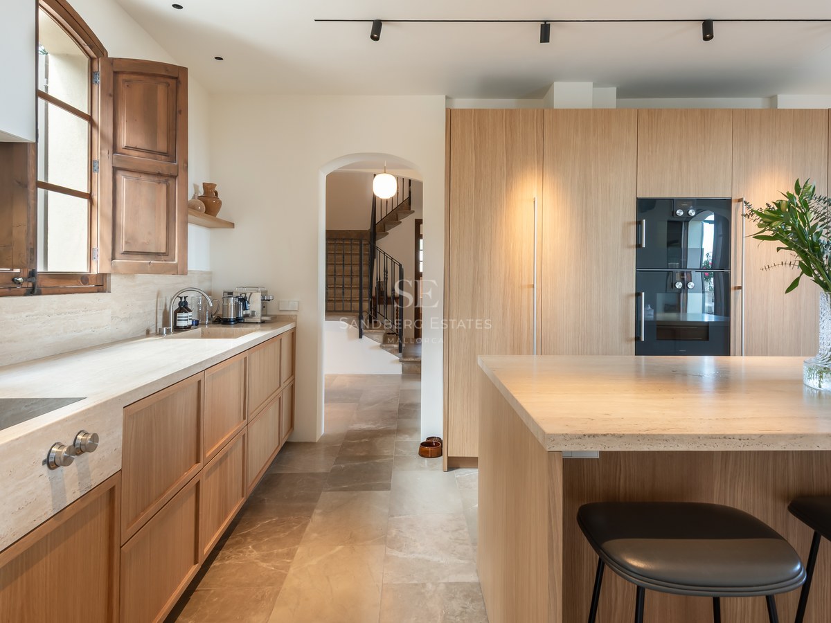 Cuisine contemporaine avec des meubles en bois clair, des plans de travail en pierre naturelle et un îlot central.
