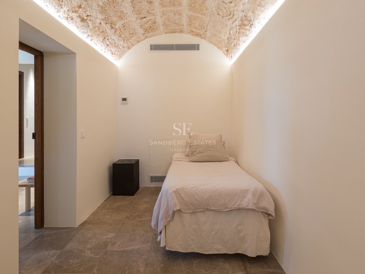 Chambre minimaliste dotée d'un plafond voûté en pierre naturelle avec éclairage indirect et sol en pierre.