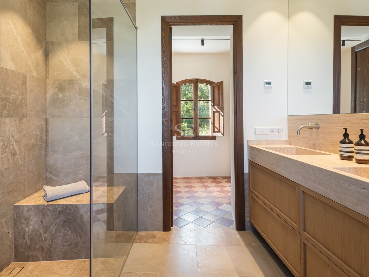 Salle de bains de luxe avec douche à l'italienne en pierre, double vasque intégrée et menuiserie en chêne.